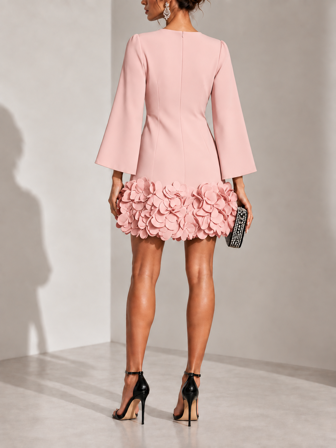 Back view of the pink dress, showing the centre zip and the 3D petal trim around the hem. 10