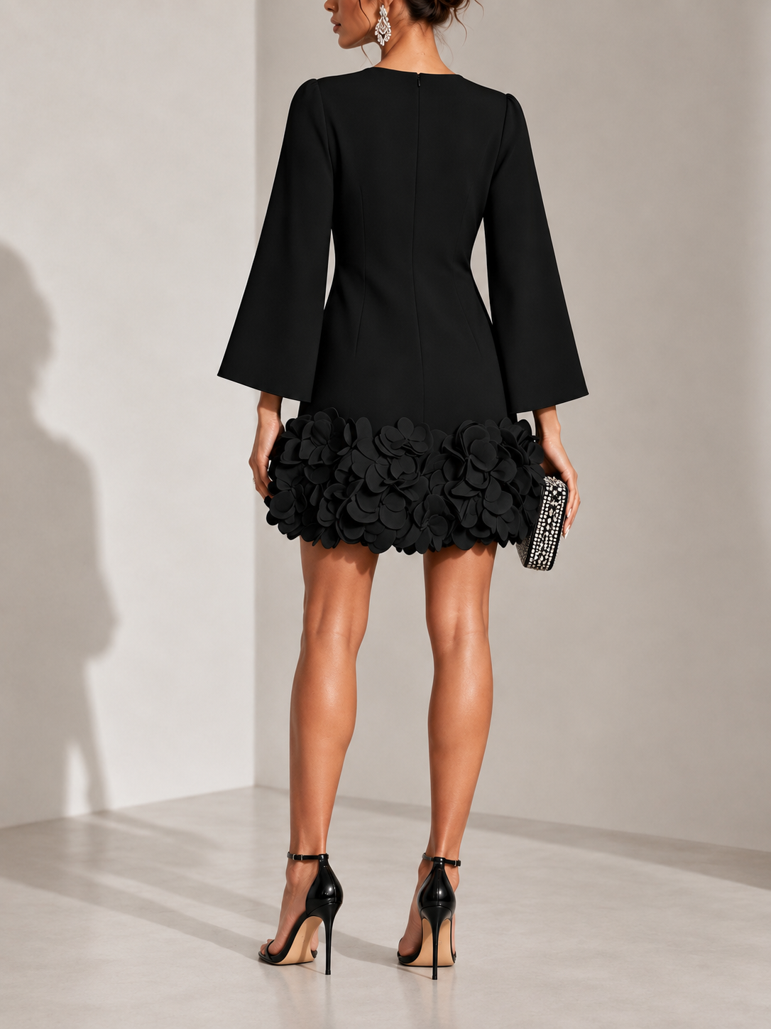 Back view of the black dress, showing the centre zip, seaming and the full petal appliqué around the hem. 3