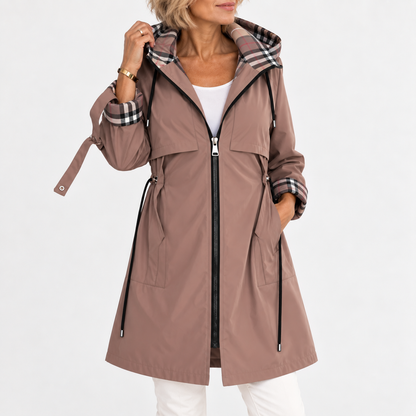 Woman wearing the hooded coat in dusky brown, zipped open over a white top, with check lining visible on hood and turned-back cuff. 1