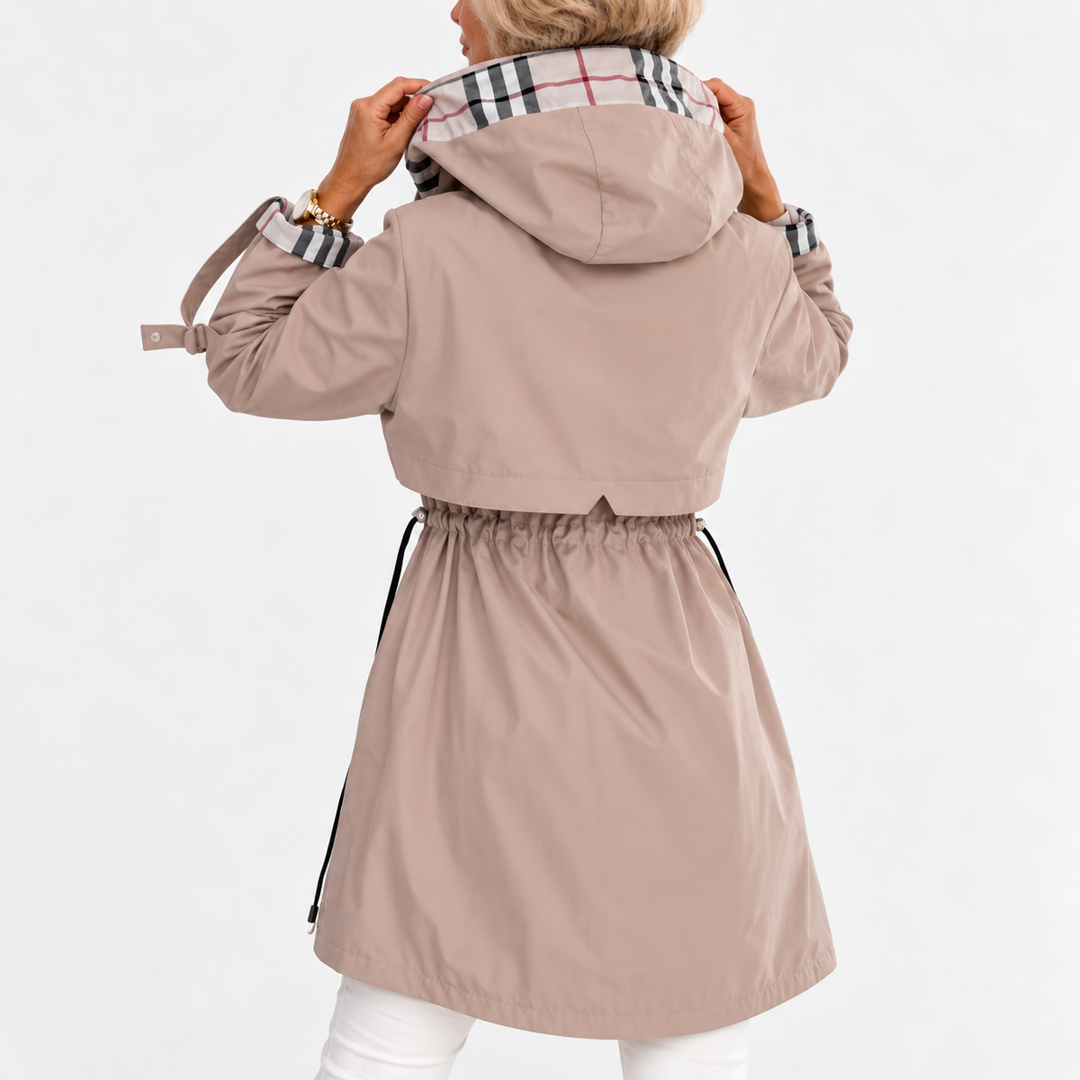 Back view of the beige coat on a model holding up the hood, showing the gathered drawstring waist and check lining. 3