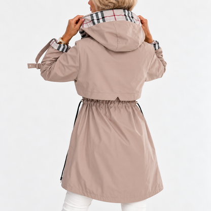 Back view of the beige coat on a model holding up the hood, showing the gathered drawstring waist and check lining. 3