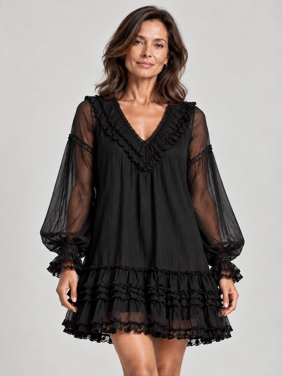 Close front view of a woman in the black mini dress, showing the ruffled V-neckline, sheer balloon sleeves and tiered hem. 1