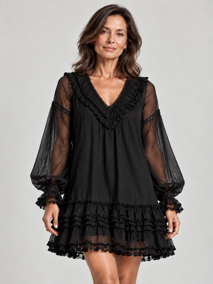 Close front view of a woman in the black mini dress, showing the ruffled V-neckline, sheer balloon sleeves and tiered hem. 1