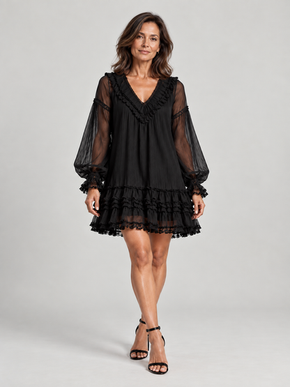 Full-length front view of a model in the black ruffled mini dress with black ankle-strap heels. 2