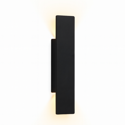 Slim black rectangular wall light seen at an angle against white, glowing warm light from its top and bottom edges. 1