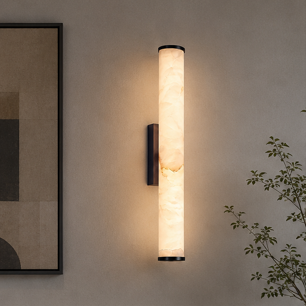 Lit vertical marble wall light with dark metal end caps and bracket, mounted on a neutral wall beside an abstract framed print. 3