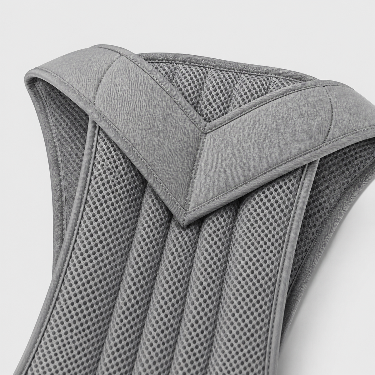 Close-up of the grey brace's padded V-shaped shoulder section and the ribbed breathable mesh panels with stitched edging. 11