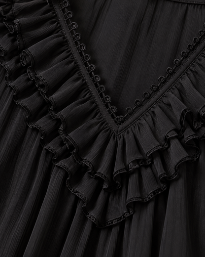 Close-up detail of the black V-neckline with layered ruffles, looped trim and the fine crinkled fabric. 5
