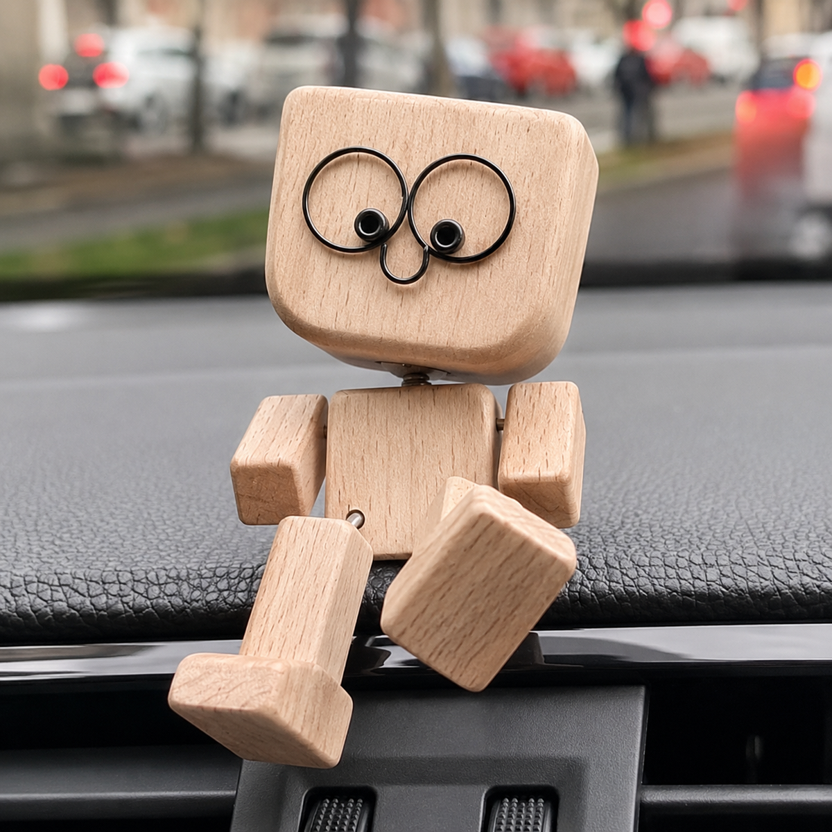 Light wooden figure with wire-ring eyes sitting on a car dashboard, legs dangling over the edge, blurred street behind. 1