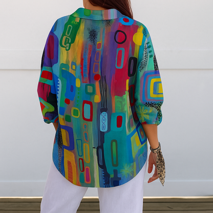 Back view of the blouse on a model, showing the continuous multicoloured abstract print, rounded hem and three-quarter sleeves with white trousers. 7