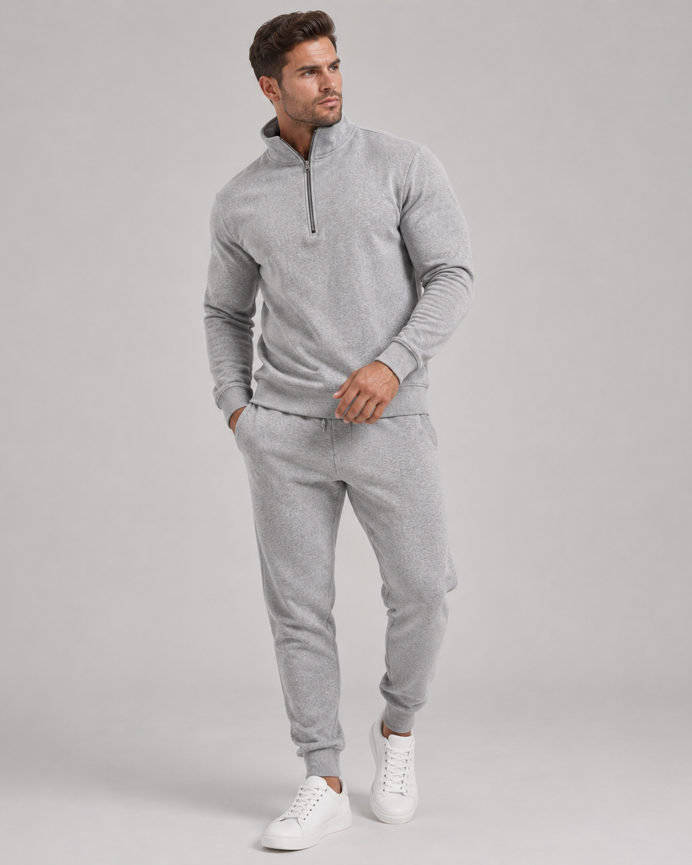 Full-length view of a model in the grey marl tracksuit with white trainers, looking to the side 1