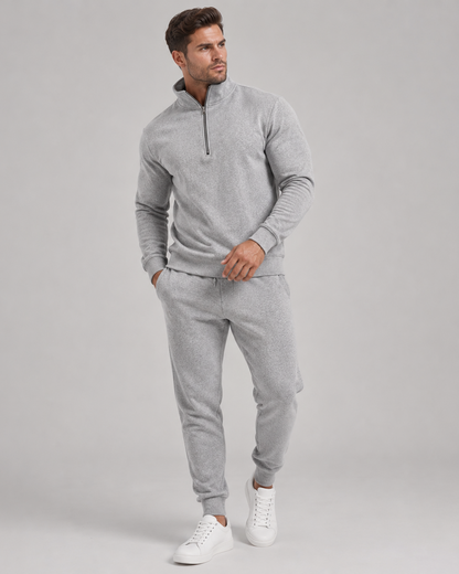 Full-length view of a model in the grey marl tracksuit with white trainers, looking to the side 1