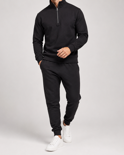 Model walking in the black tracksuit set with white trainers, hand in trouser pocket 3