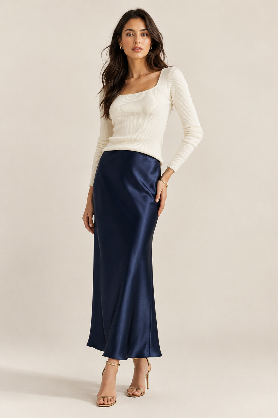 Full-length view of the cream ribbed top styled with a navy satin skirt and gold heels 4