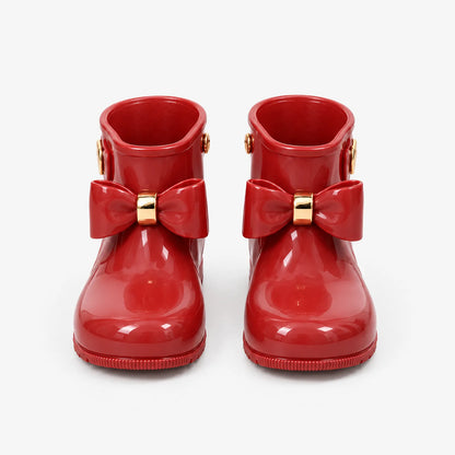 Front view of a pair of glossy red wellies with gold-trimmed bows, shown on a plain white background. 2