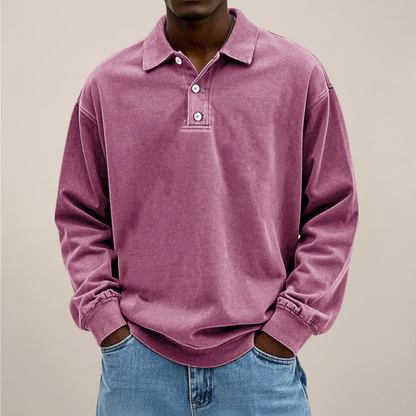 Model wearing the relaxed-fit long sleeve polo in washed dusky pink, hands in the pockets of light blue jeans. 10