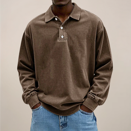 Model wearing the relaxed-fit long sleeve polo in washed chocolate brown, hands in the pockets of light blue jeans. 3