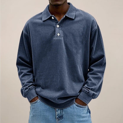 Model wearing the relaxed-fit long sleeve polo in washed dark navy blue, hands in the pockets of light blue jeans. 5