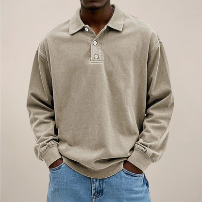 Model wearing the relaxed-fit long sleeve polo in washed sandy beige, hands in the pockets of light blue jeans. 6