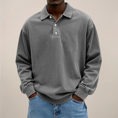 Model wearing the relaxed-fit long sleeve polo in washed mid grey, hands in the pockets of light blue jeans. 7