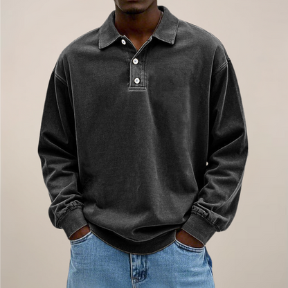 Model wearing the relaxed-fit long sleeve polo in washed charcoal black, hands in the pockets of light blue jeans. 8