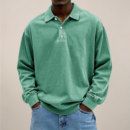 Model wearing the relaxed-fit long sleeve polo in washed sage green, hands in the pockets of light blue jeans. 9