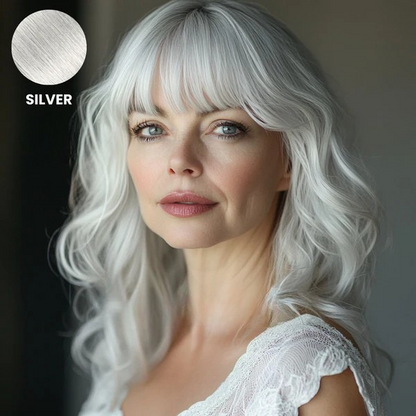 Older woman with wavy silver white hair and a full fringe, with a colour swatch 10