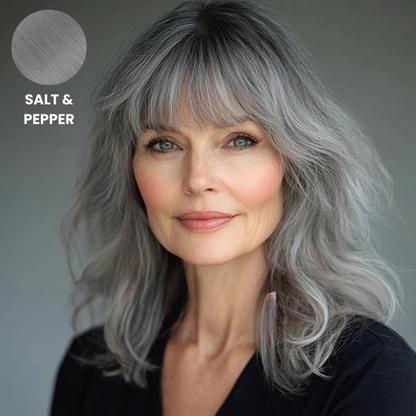 Older woman with wavy salt and pepper grey hair and a fringe, with a colour swatch 9