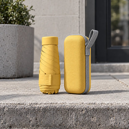 Folded yellow umbrella and its matching yellow zipped case with grey loop, standing on a concrete step outdoors. 3