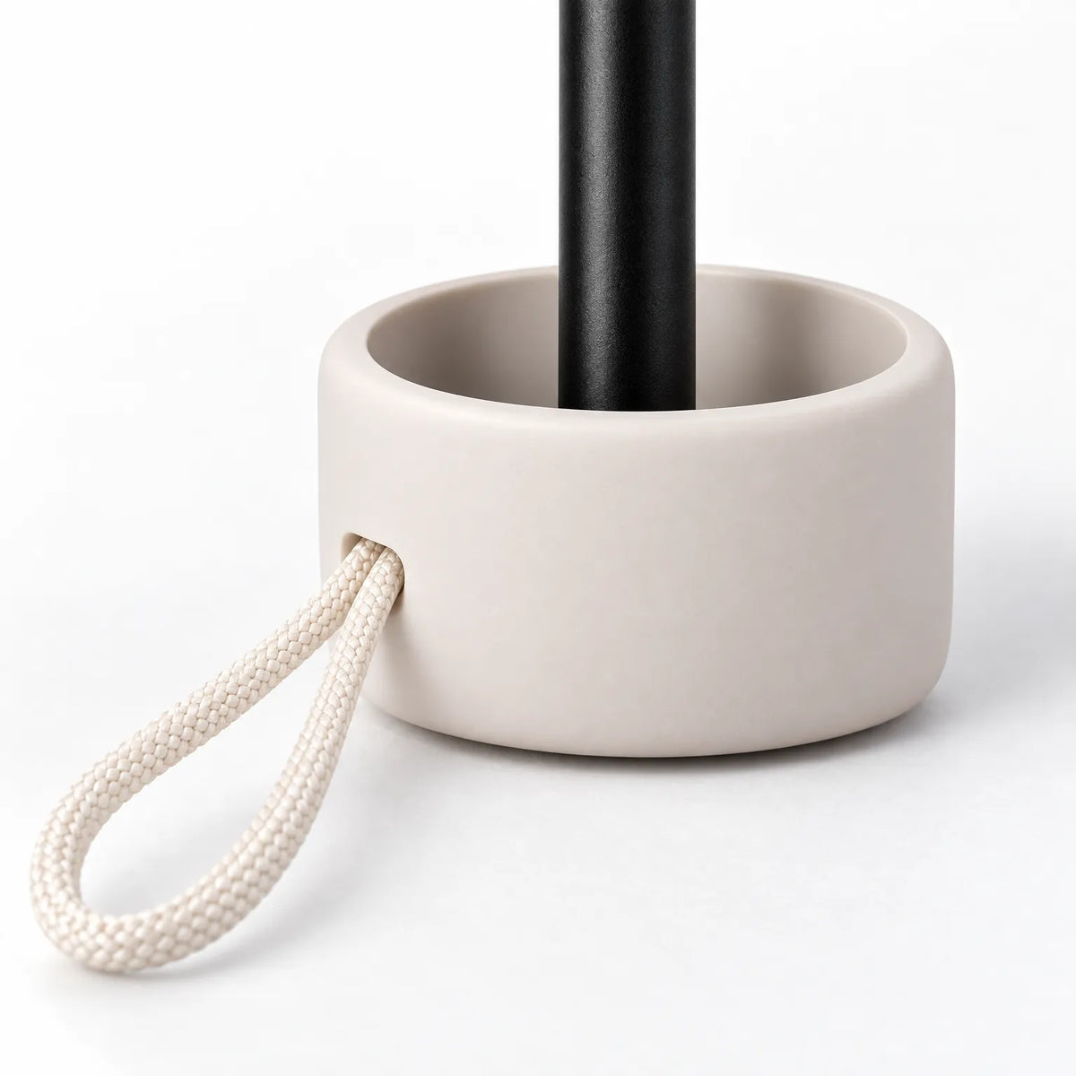 Close-up of the cream rounded handle base with a braided cream loop cord, with the black shaft rising from it. 5