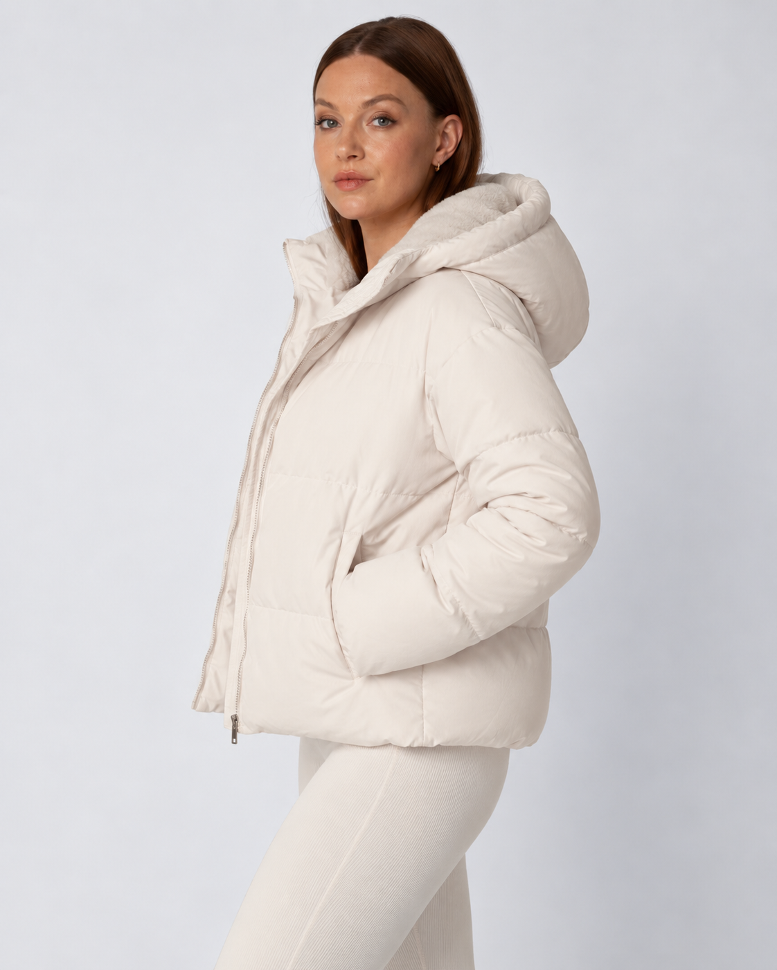 Side view of the cream puffer jacket with hood up, model's hand in the pocket 3