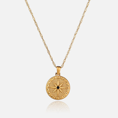 Front view of a round gold pendant with a raised eight-pointed star and black stone, hanging from a twisted chain. 1