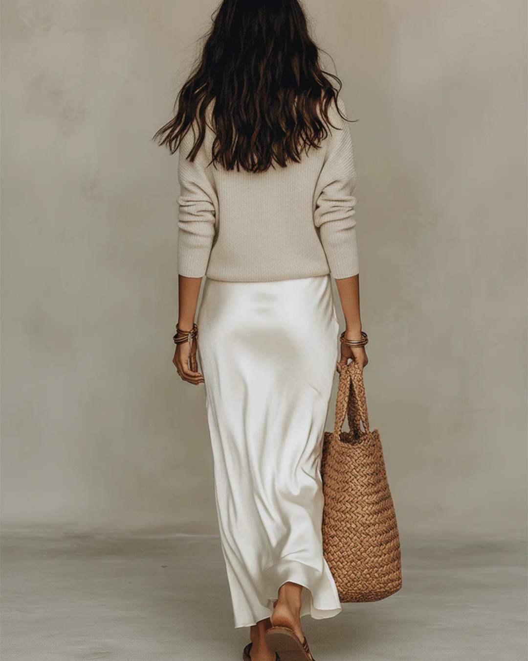Back view of a model in the cream satin midi skirt and beige knit jumper 9
