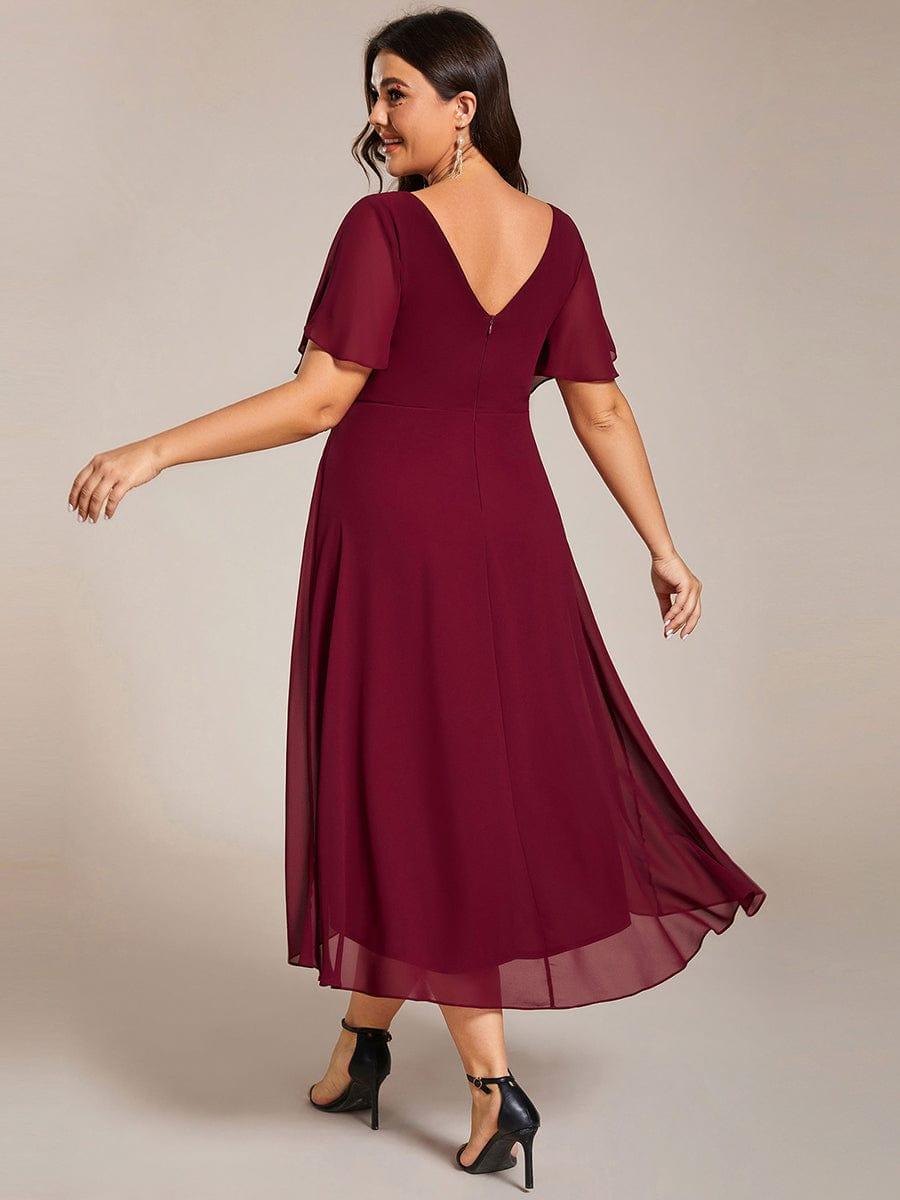 Back view of the burgundy dress on a plus-size model, showing the deep V back, centre zip and flowing chiffon hem. 50
