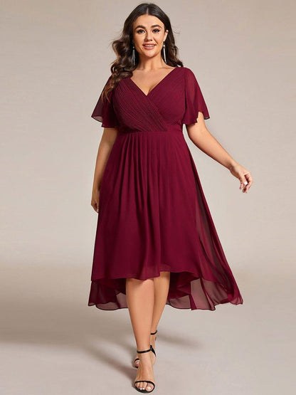 Plus-size model in the burgundy high-low dress with flutter sleeves, wearing long drop earrings and black heels. 49