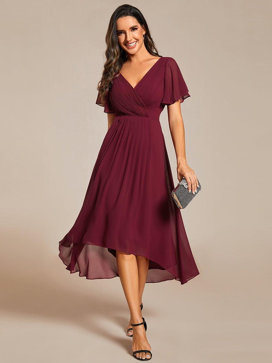 Front view of the burgundy chiffon dress on a model holding a sparkly clutch, with pleated wrap bodice. 3