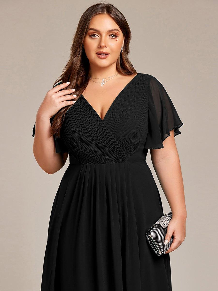 Close-up of the black dress on a plus-size model, showing the pleated wrap bodice and sheer sleeves, holding a sparkly clutch. 28