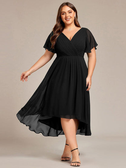 Plus-size model in the black chiffon dress, front view with the skirt swishing out to one side, wearing black heels. 26