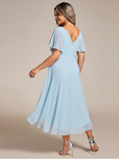 Back view of the light blue chiffon dress on a plus-size model, showing the V back, central zip and swishing hem. 90