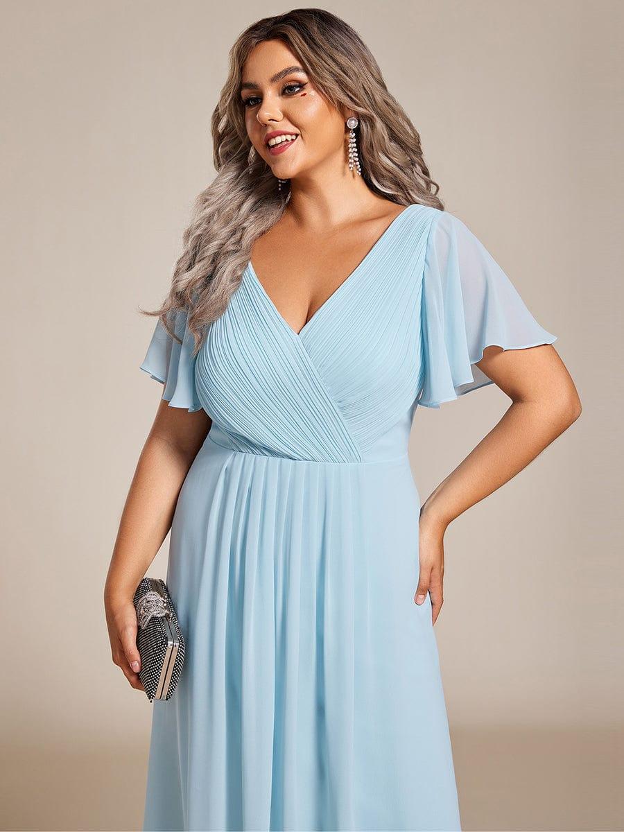 Close-up of the light blue pleated V-neck bodice and sheer flutter sleeves on a plus-size model with a sparkly clutch. 91