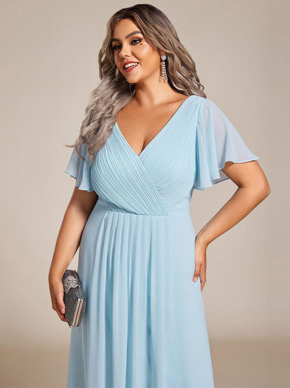 Close-up of the light blue pleated V-neck bodice and sheer flutter sleeves on a plus-size model with a sparkly clutch. 91