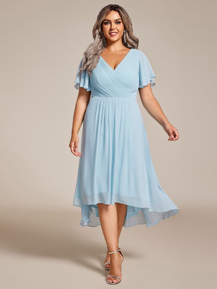 Plus-size model wearing the light blue chiffon dress with pleated wrap bodice, flutter sleeves and silver strappy heels. 89