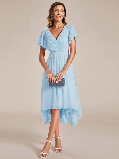 Model in the light blue chiffon dress holding a small beaded clutch, showing the shorter front and longer back hem. 87