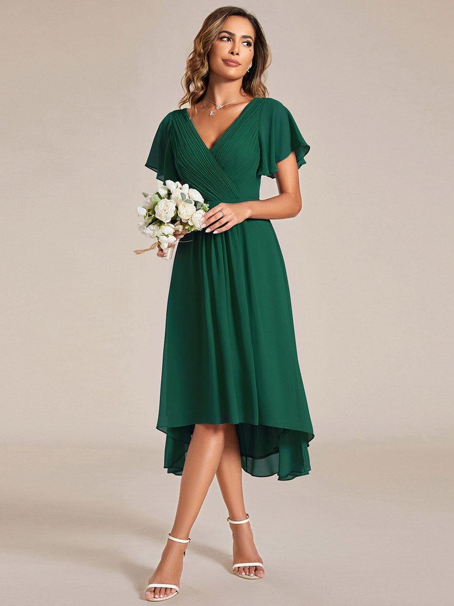 Emerald green dress worn with a bouquet of white roses, showing the flowing high-low chiffon skirt. 13