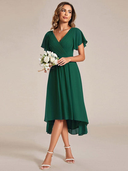 Emerald green dress worn with a bouquet of white roses, showing the flowing high-low chiffon skirt. 13