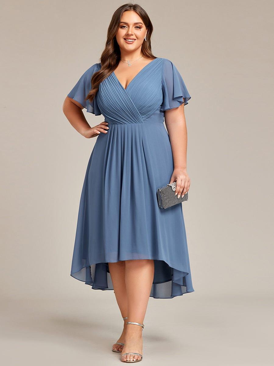 Plus-size model in the dusty blue high-low chiffon dress, hand on hip, holding a black sparkly clutch, front view. 44