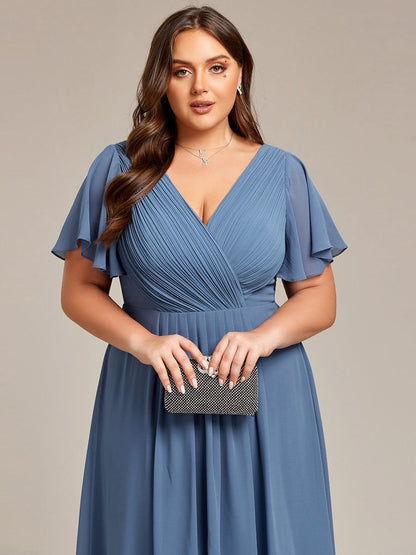 Close-up of the pleated wrap V-neck bodice and flutter sleeves in dusty blue, with the model holding a sparkly clutch. 43