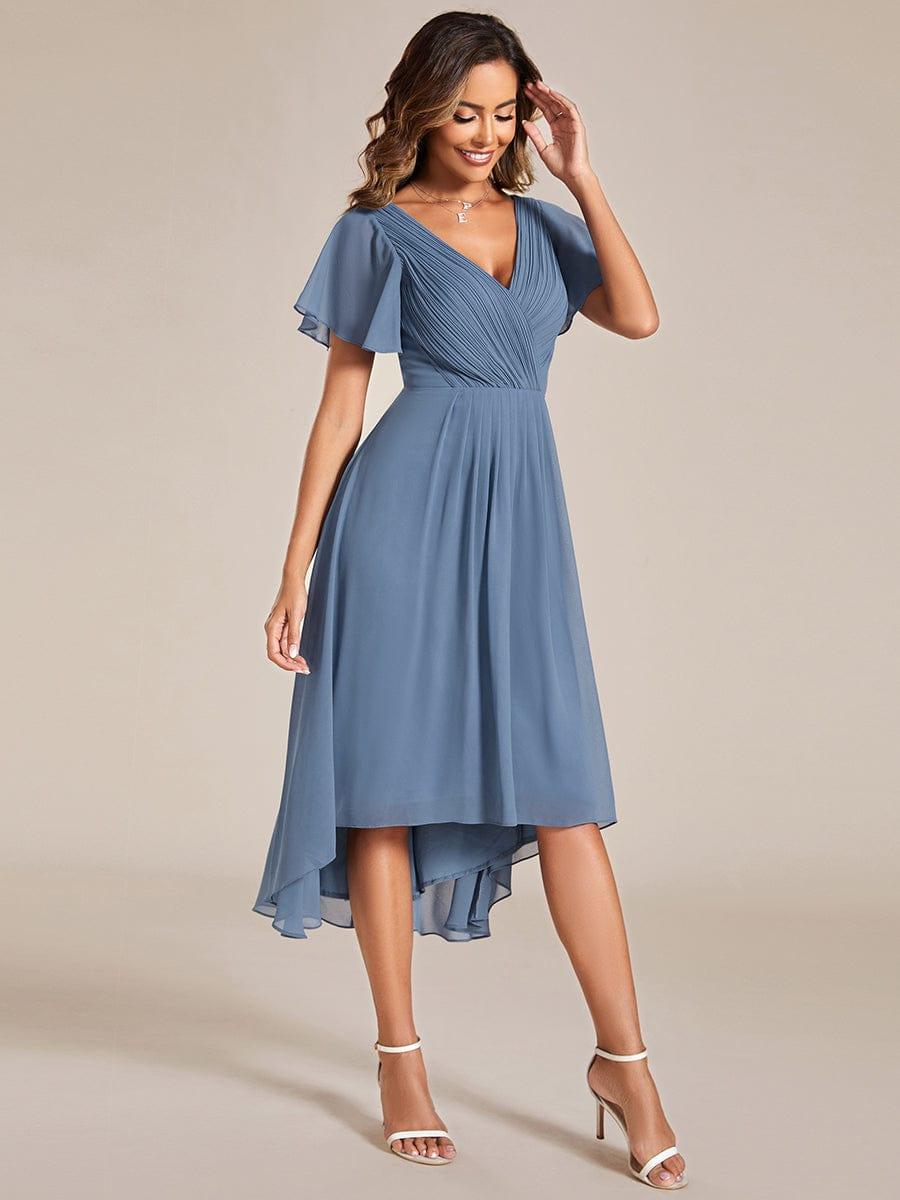 Dusty blue dress from a three-quarter angle, with the model's hand to her hair and the hem swirling. 9