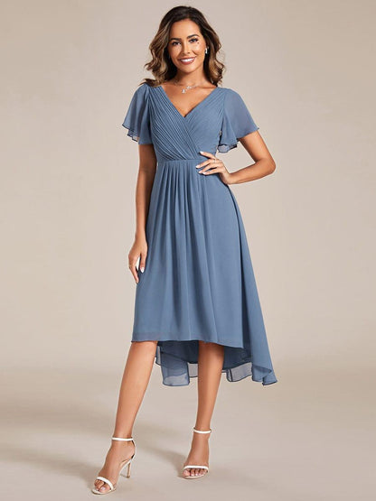 Dusty blue version worn by a model with one hand on hip, white heeled sandals and a pleated V-neck bodice. 5