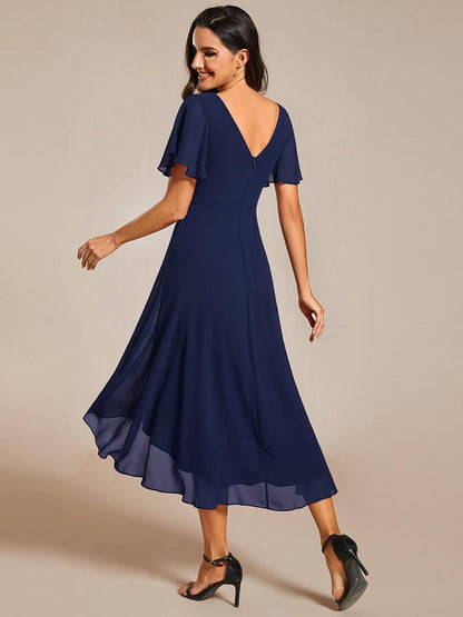 Back view of the navy dress on a model, showing the low V back, zip and flutter sleeves. 2